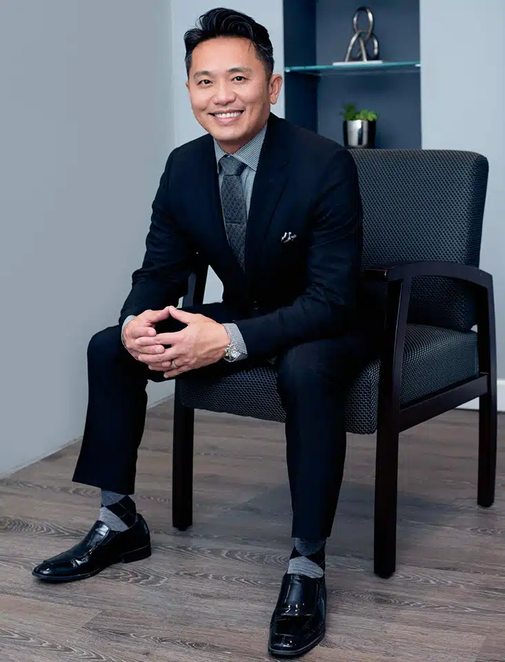 A man in a suit, Dr. Truong, sitting on a chair.